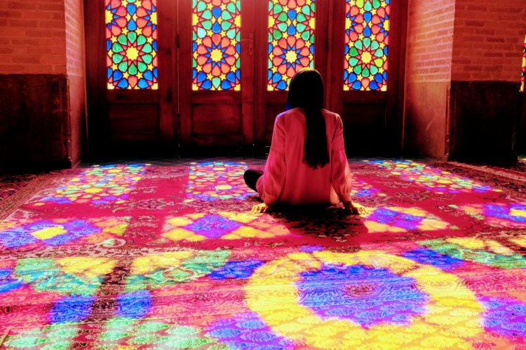 Femme assise devant les vitraux de la Mosquée Rose